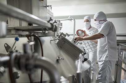 Three people working in a dairy processing plant