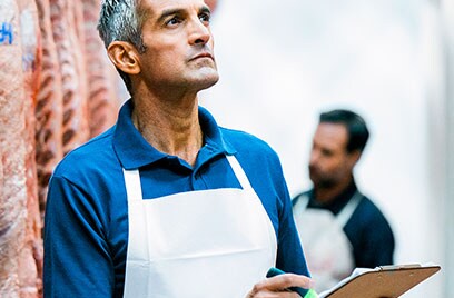 A worker at a cold storage writing something on a clipboard