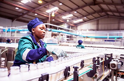 A woman working in a factory standing next to a conveyor belt