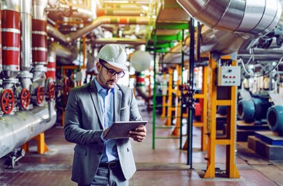 An engineer standing in an industrial plant while checking his tablet